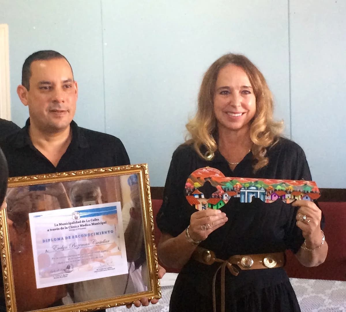 Evelyn Castellar displaying the Key to the City beside a framed certificate of recognition